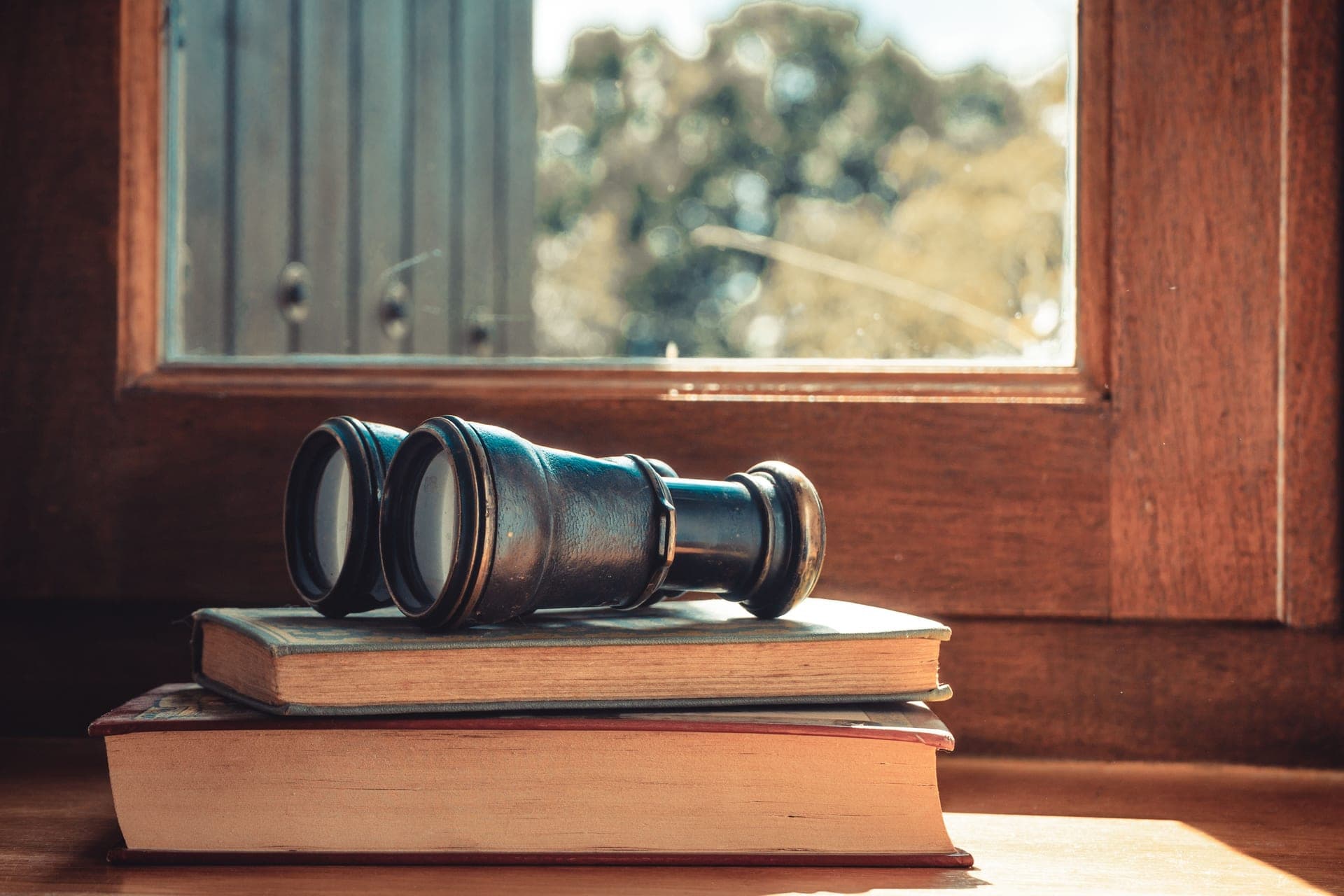 Binoculars and a notebook beside a window
